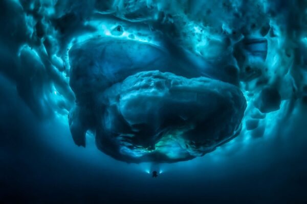 Iceberg with a diver underneath it with video lights shining on the iceberg,  supported by Northern Explorers A/S, Tasiilaq, East Greenland, Atlantic Ocean, Arctic, Northpole, Icebergs.